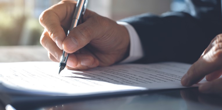 Hånd med kuglepen skriver på papir